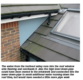 The water from the inclined valley runs into the roof window side flashing and overloads it. Also the high level down-pipe could have been moved to the brickwork and connected into the lower down-pipe to avoid additional water running down the roof tiles, but would have needed a little more pipe work
